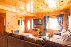 Ein gemütliches Holzhaus-Interieur mit einer Couch, einem Fernseher und einem Kamin.