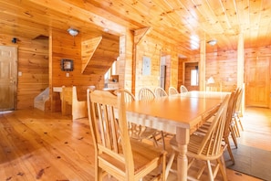 Ein Holzblockhaus-Interieur mit Esstisch und Stühlen, einer Küchenzeile und einer Treppe.