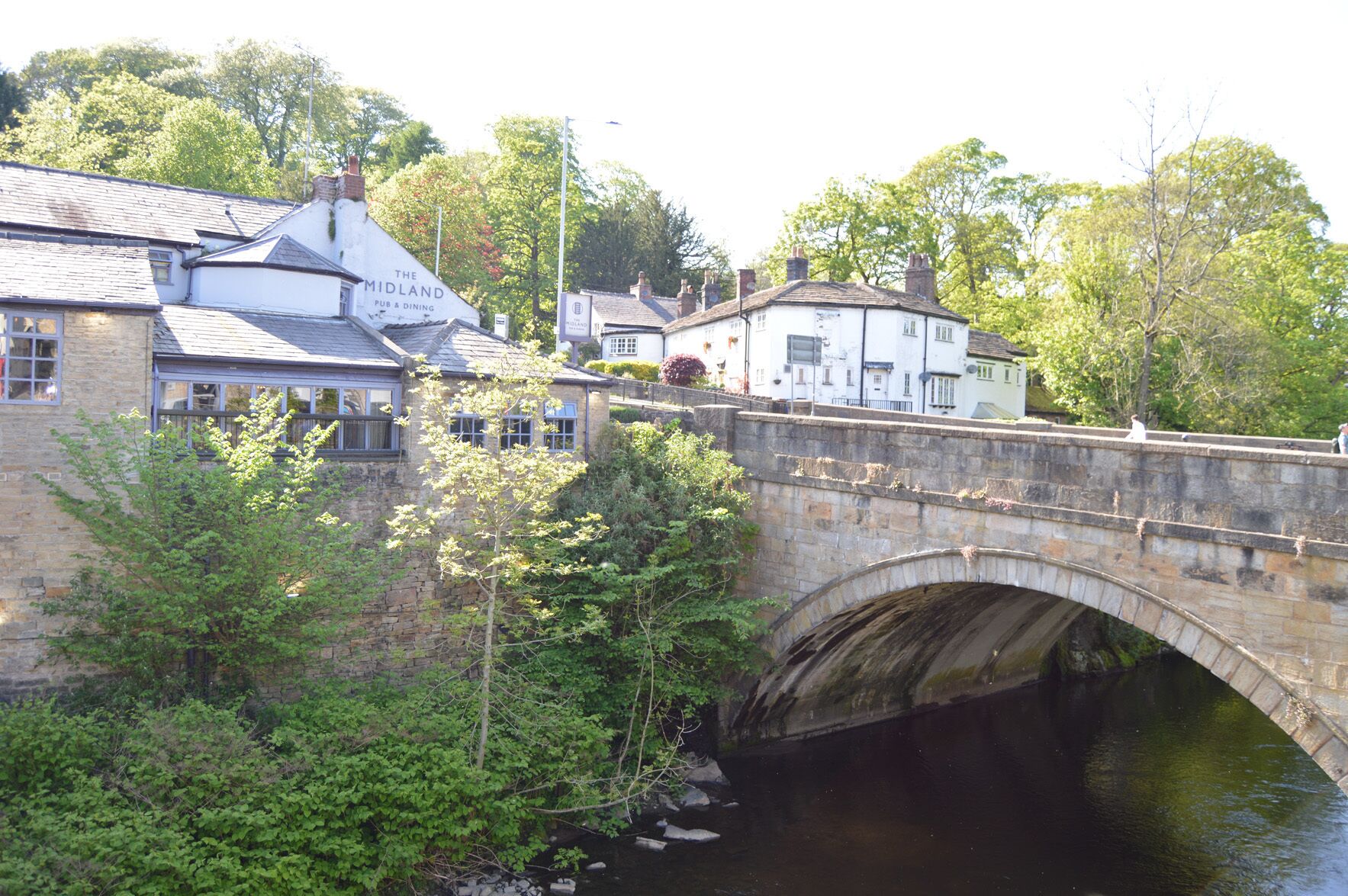 A stone bridge over a river with a pub named "The Midland" on the left.