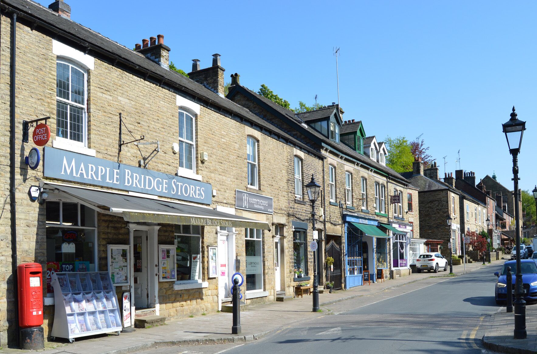 A street view with the Marple Bridge Stores and a Harry Thomas sign.