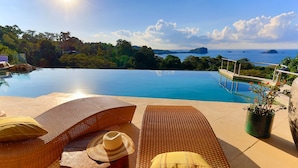 A poolside area with lounge chairs, a sun umbrella, and a potted plant. - 6BR Luxury Ocean View Villa • Infinity Pool • Private Cinema • Spa (Quepos)