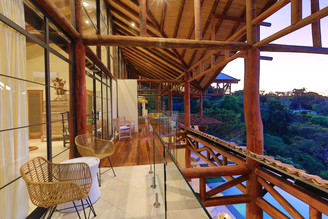 Ein geräumiger Balkon mit Holzbalkon, Korbstühlen und Blick auf üppiges Grün.