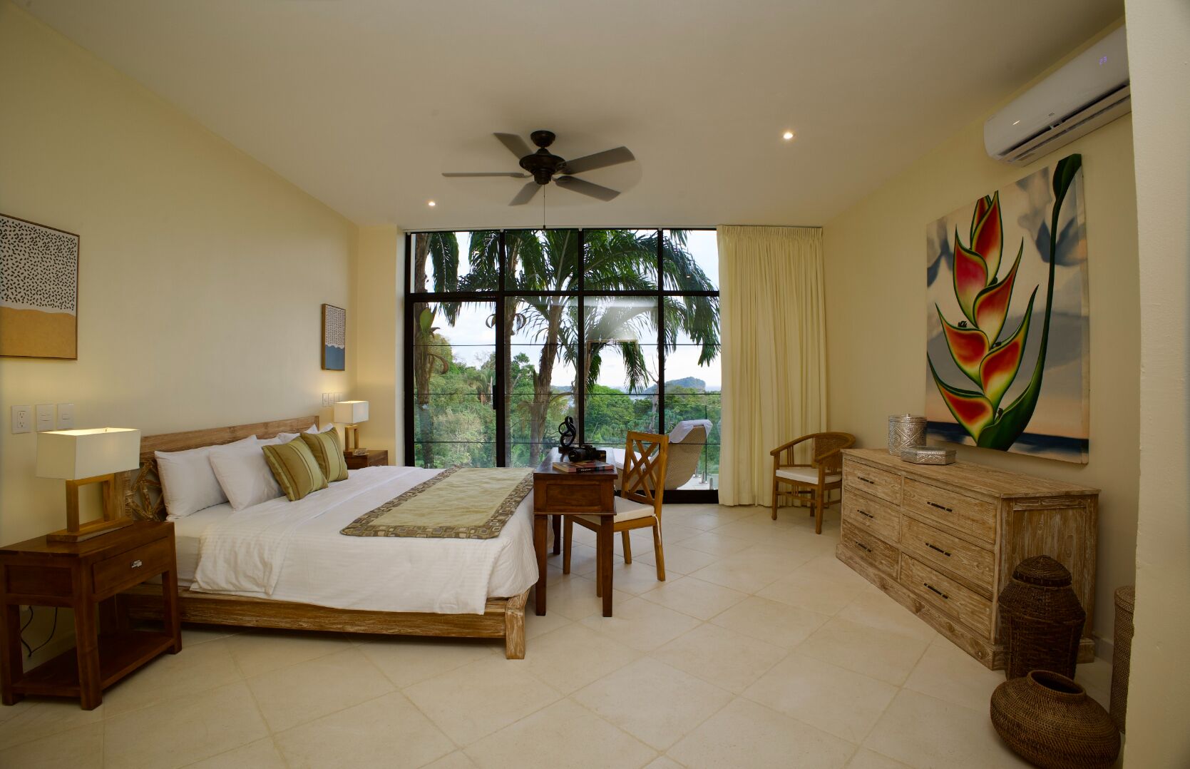 A bedroom with a bed, a desk, a chair, a dresser, and a ceiling fan.