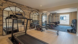 Un gimnasio en casa con una cinta de correr, banco de pesas y diverso equipo de ejercicio.