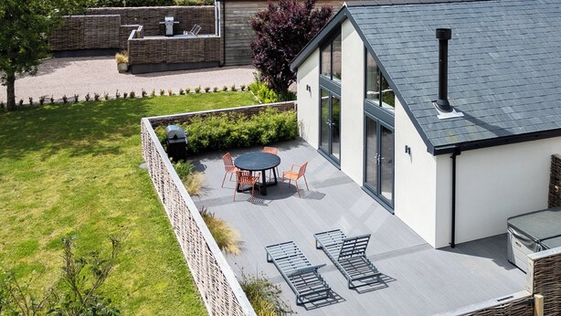 Una casa moderna con un patio, una zona de barbacoa y vistas del paisaje circundante.