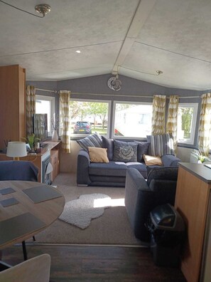 Cozy living space with a kitchenette and seating area, offering a view of the outside through large windows.
