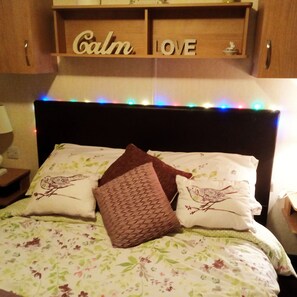 Restful retreat with a floral-patterned bedspread and a shelf featuring two compartments, 'Calm' and 'Love'.
