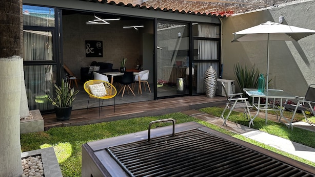 A modern outdoor patio with a dining area, a grill, and a seating arrangement.