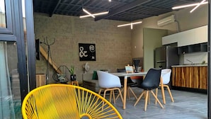 A modern interior with a dining area, kitchen, and seating with a brick wall and artwork.
