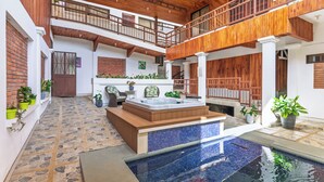 A spacious indoor pool area with a hot tub, wooden balconies, and potted plants. - Hotel Ribera La Paz (Piedades Norte)