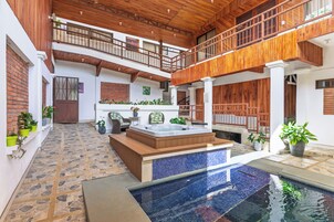 A spacious indoor pool area with a hot tub, wooden balconies, and potted plants.