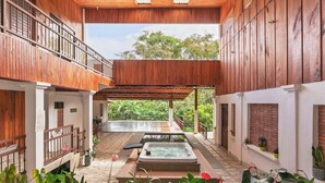 A spa area with a hot tub and a pool, surrounded by wooden walls and potted plants. - Hotel Ribera La Paz (Piedades Norte)