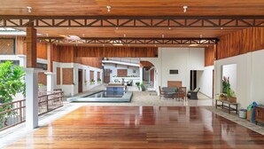 A spacious indoor area with a wooden floor, a central water feature, and a seating area with a view of a building in the background. - Hotel Ribera La Paz (Piedades Norte)