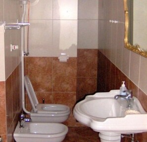 A bathroom with two toilets, a sink, and a mirror.