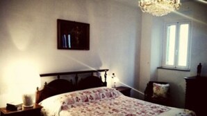 Une chambre à coucher comprenant un lit, une table de chevet, une commode, une fenêtre et un lustre.