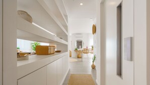 A modern kitchen with white cabinetry, a built-in island, and a woven rug leading to a dining area.