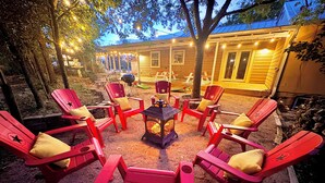 An outdoor seating area with red Adirondack chairs arranged around a central fire pit. - 1 Block From W Main St - Quiet Spacious Getaway (Fredericksburg)