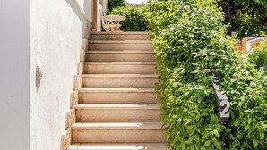 Un escalier menant à une terrasse en bois, sur laquelle on peut voir un panneau portant le chiffre « 2 », le tout étant entouré de verdure.