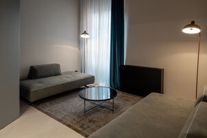 Un soggiorno moderno con un divano grigio, un tavolino rotondo e una lampada da terra.