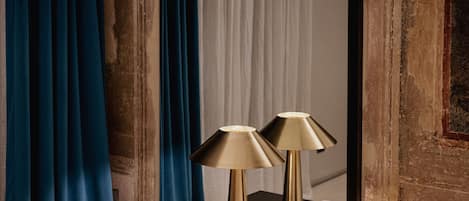 Un dormitorio con una cama, dos lámparas de noche, una mesita de noche de madera oscura y cortinas azules.