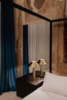 Una camera da letto con un letto, due abat-jour, un comodino in legno scuro e tende blu.