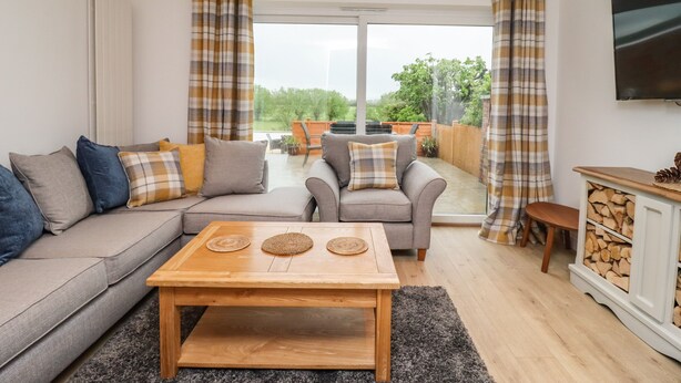 A living room with a sofa, two armchairs, a coffee table, and a TV. - Delabere Road (Cheltenham)