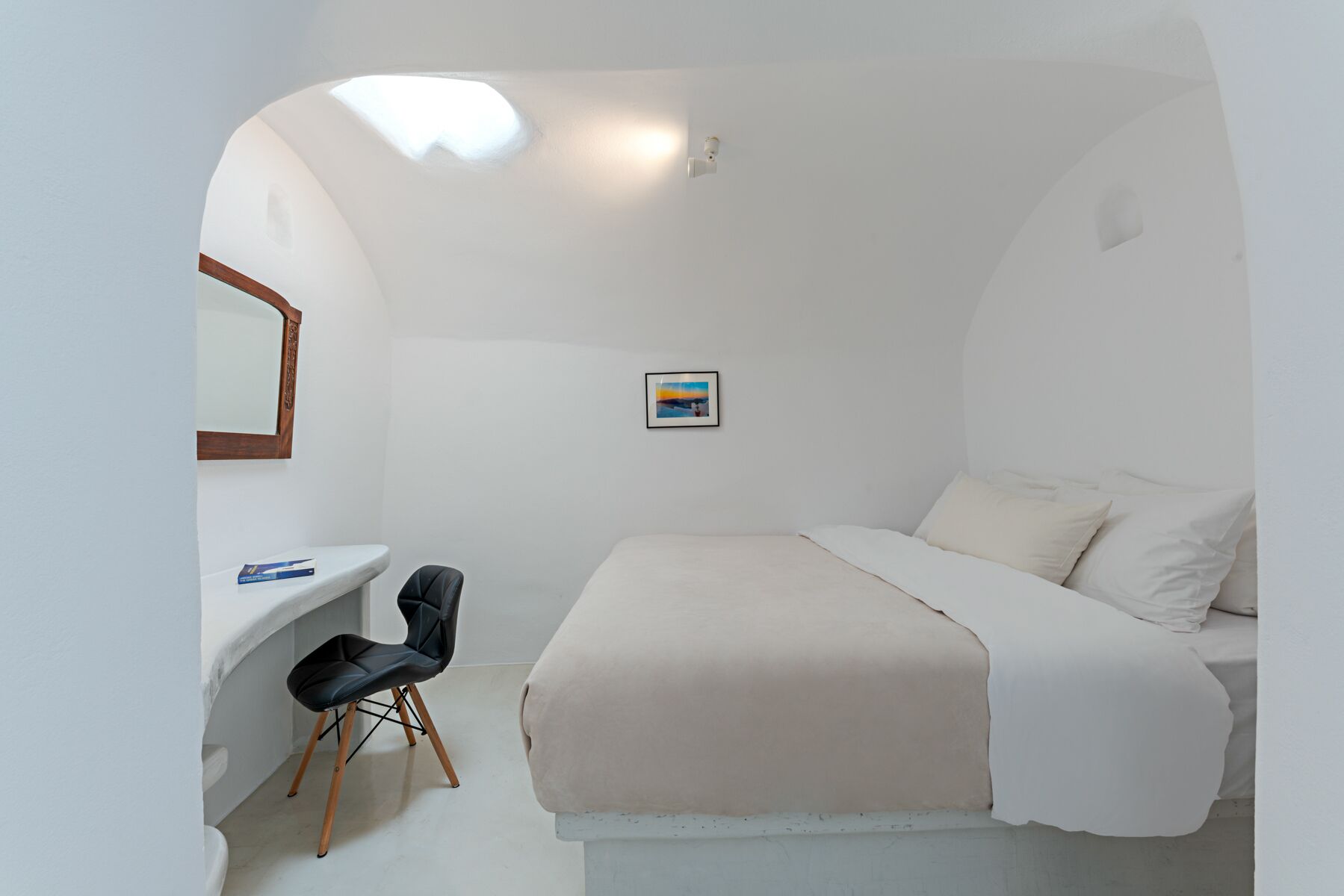 A bedroom with a bed, a desk, a chair, a mirror, and a picture on the wall.