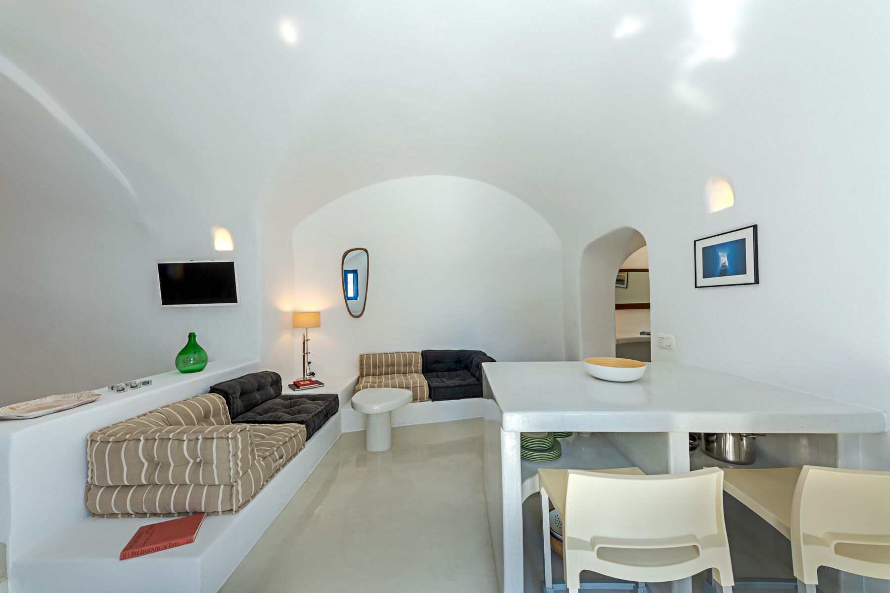 A modern living room with a sofa, a dining table with chairs, a TV, and a lamp.