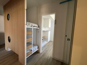 Ein Zimmer mit Etagenbett, einem Kleiderschrank und einer Tür zu einem weiteren Raum.