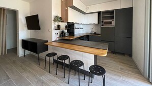 Eine moderne Küche mit Kochinsel, Barhocker, Mikrowelle und Einbauofen.