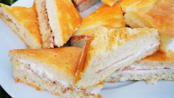 A plate of triangular sandwiches with visible fillings, held by a person wearing a bracelet.