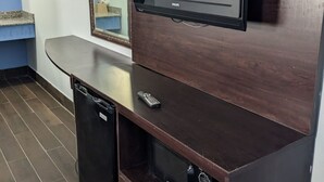 Une petite cuisine équipée comprenant un four à micro-ondes encastré, un petit réfrigérateur et un téléviseur à écran plat fixé au mur.