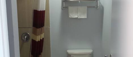 Un baño pequeño con inodoro, ducha y perchero.