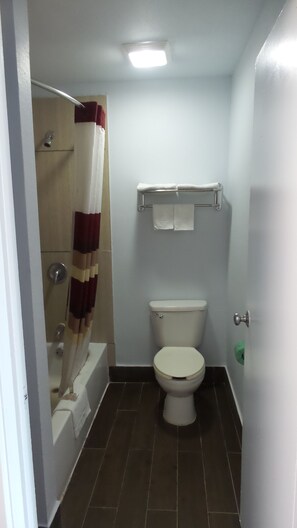 A small bathroom with a toilet, a shower, and a towel rack.