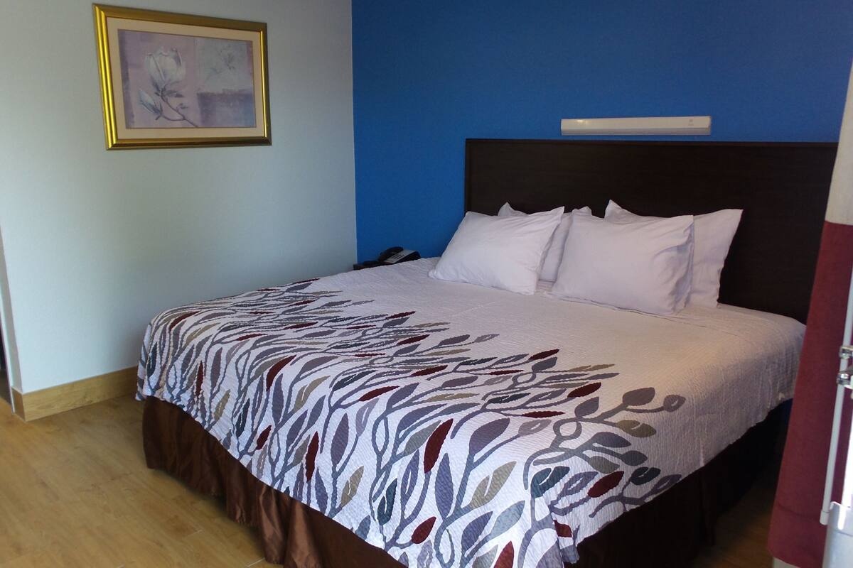 A neatly made bed with a patterned bedspread, a dark headboard, and white pillows.
