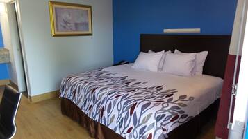 Una cama bien hecha con una colcha estampada, un cabecero oscuro y almohadas blancas.