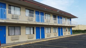 Un motel composé d’un bâtiment à deux étages, avec des portes bleues et des balcons dotés de rampes blanches.