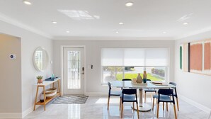 Un espace de salle à manger lumineux et moderne, doté d’une grande fenêtre, d’un grand miroir rond et d’une table avec des chaises.