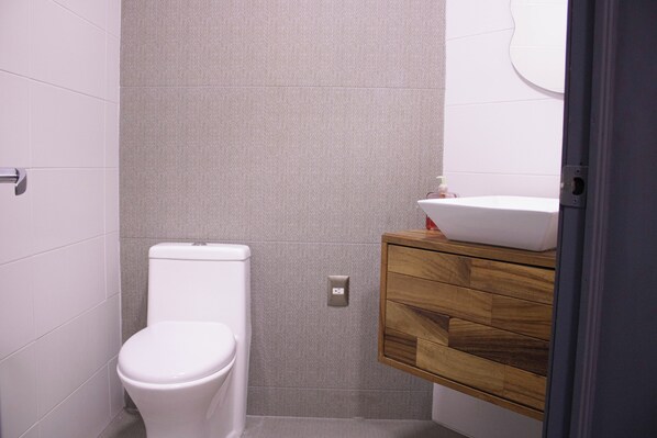 Une salle de bain avec des toilettes, un meuble-lavabo en bois et un mur à texture.