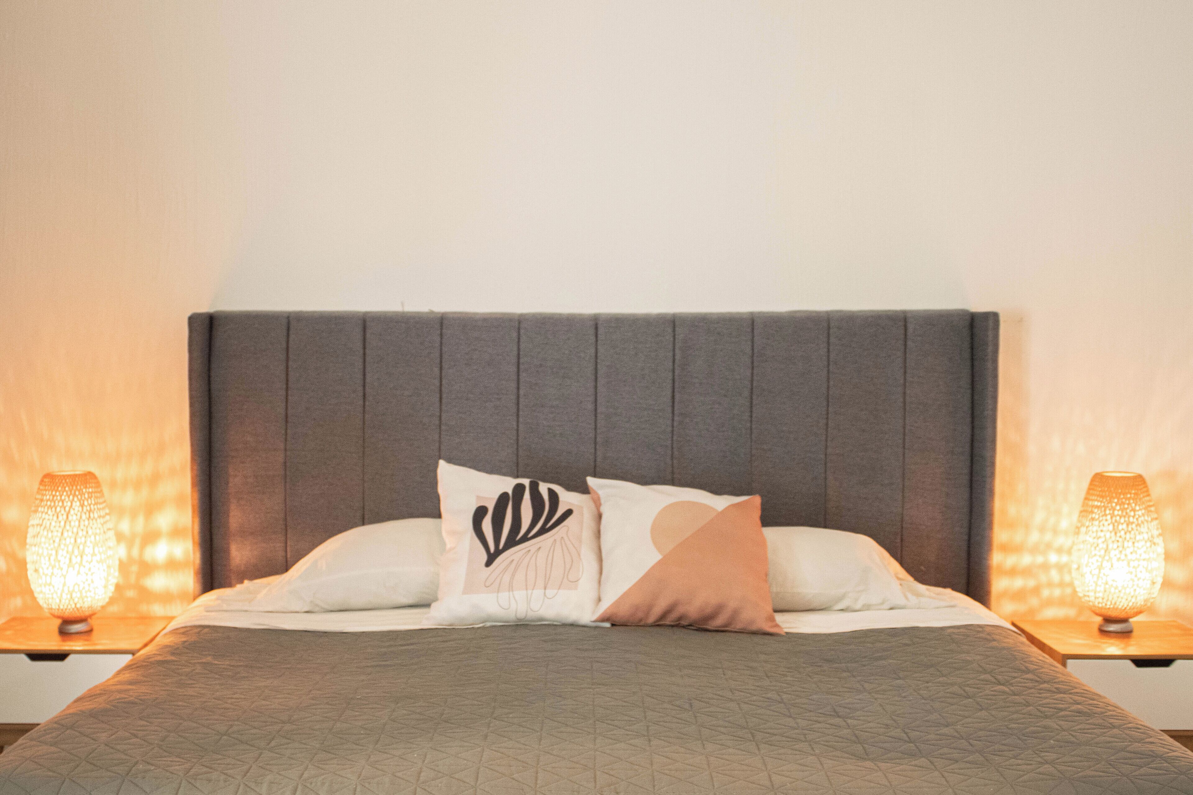 A neatly made bed with a quilted bedspread, two pillows with a leaf design, and a headboard.