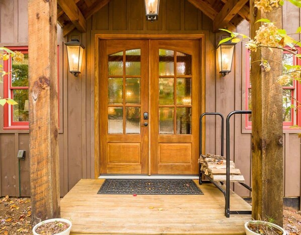 A wooden front door with glass panels, a wooden porch, and two wall-mounted lanterns. - Laurel Mountain Chalet (Blue Ridge)