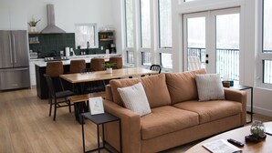 Eine moderne Küche mit Essbereich, einer Couch und großen Fenstern.