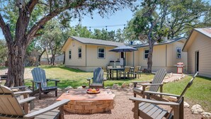 A backyard with Adirondack chairs, a fire pit, and a dining table with chairs. - Canyon Lake Vacation Rental < 1/2 Mi to Water! (Canyon Lake)