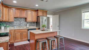 A modern kitchen with wooden cabinets, granite countertops, and a central island with bar stools. - Canyon Lake Vacation Rental < 1/2 Mi to Water! (Canyon Lake)