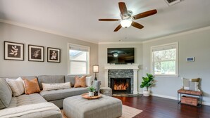 A living room with a sectional sofa, a fireplace, a ceiling fan, and framed artwork on the wall. - Canyon Lake Vacation Rental < 1/2 Mi to Water! (Canyon Lake)