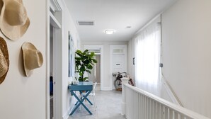 A hallway with a blue table and chairs, a potted plant, and a bicycle in the background. - Charming Coastal Getaway: Explore and Relax in our 2 Bedroom Downtown Rental (Colonial Beach)