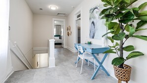 A hallway with a blue desk and chairs, a potted plant, and a painting on the wall. - Charming Coastal Getaway: Explore and Relax in our 2 Bedroom Downtown Rental (Colonial Beach)