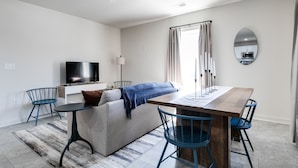 A modern living room with a sofa, TV, and dining table with chairs.