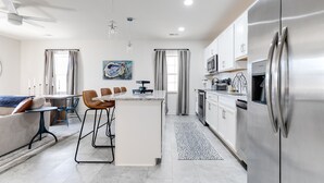 A modern kitchen with a central island, stainless steel appliances, and a dining area with bar stools.