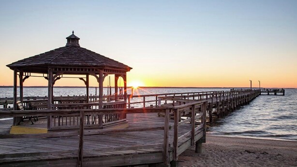 A wooden pier extending into calm waters at sunset.